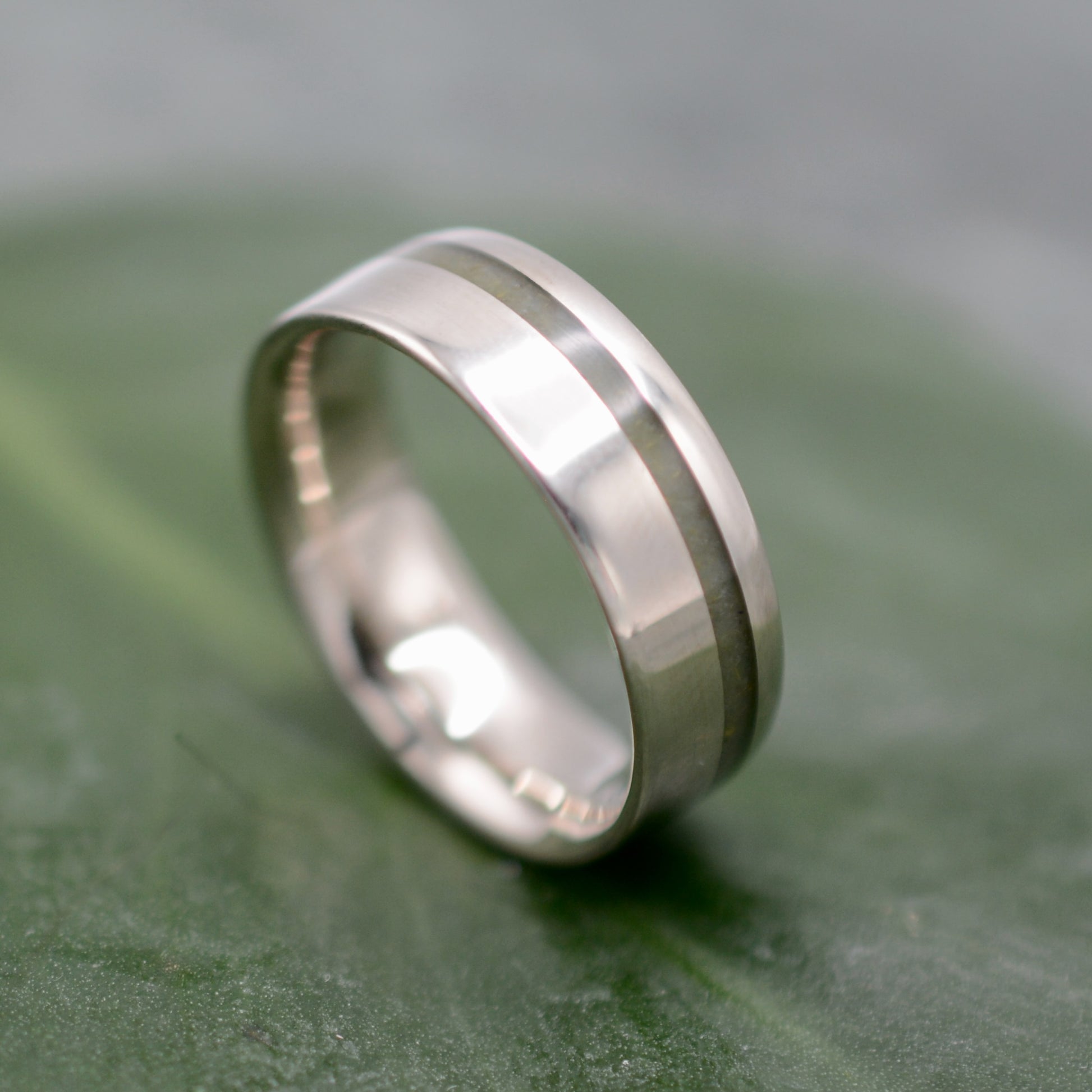 a wedding ring with a thin band on a green surface