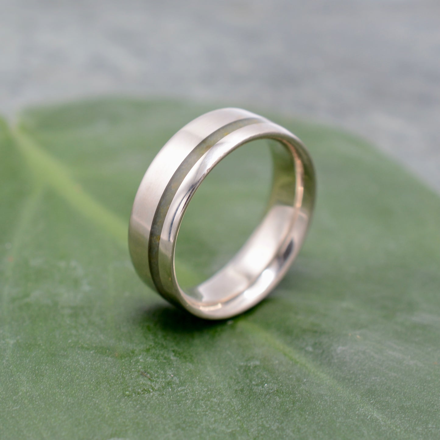 a wedding ring sitting on top of a green leaf