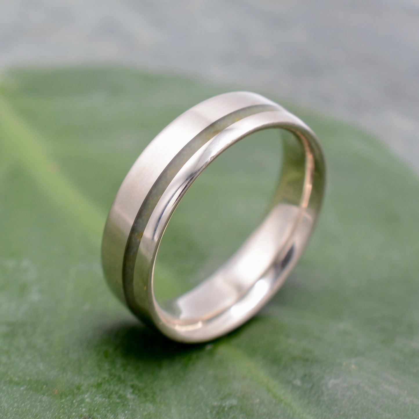 a wedding ring sitting on top of a green leaf