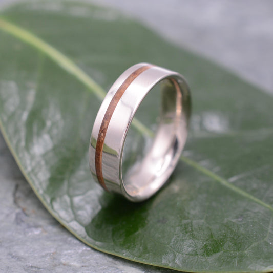 a silver ring with a brown stripe on top of a leaf