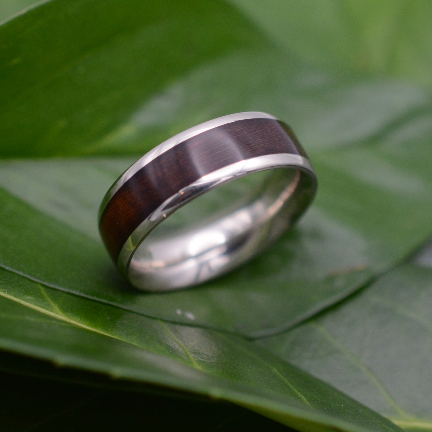 a wedding ring sitting on top of a green leaf