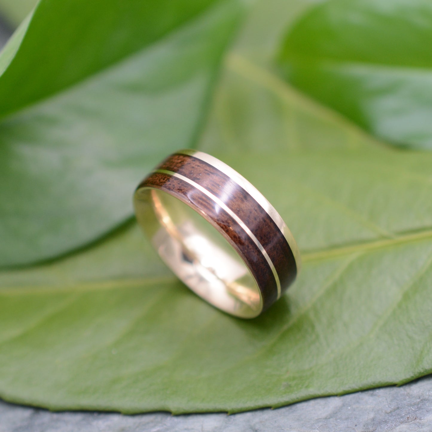 a wooden ring sitting on top of a green leaf