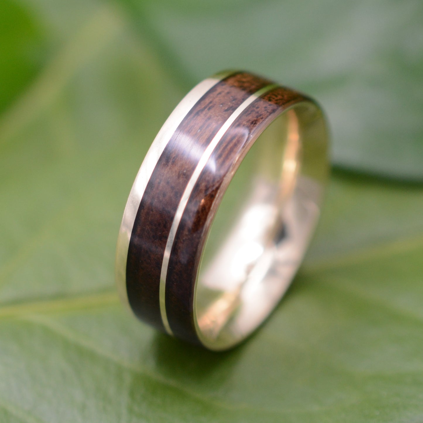 a wedding ring with a wooden inlay on a green leaf