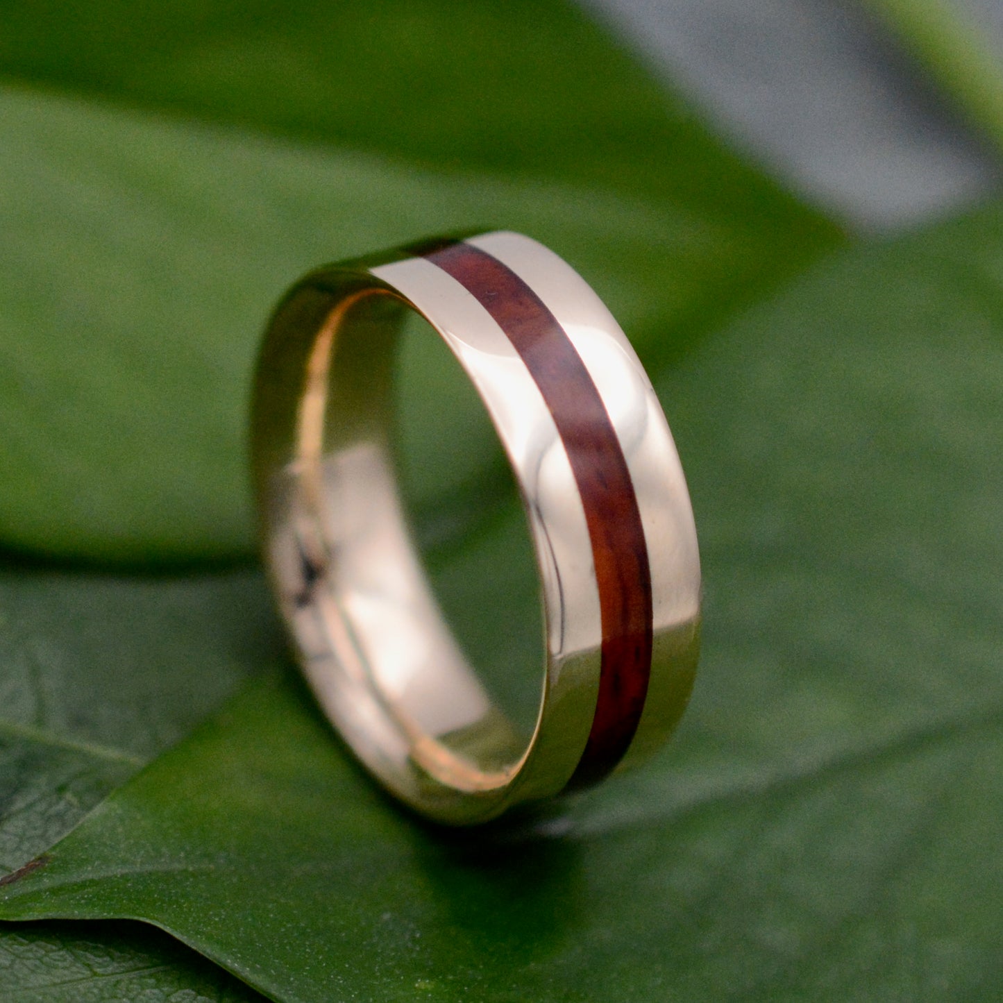 a gold ring with a wooden inlay on a green leaf