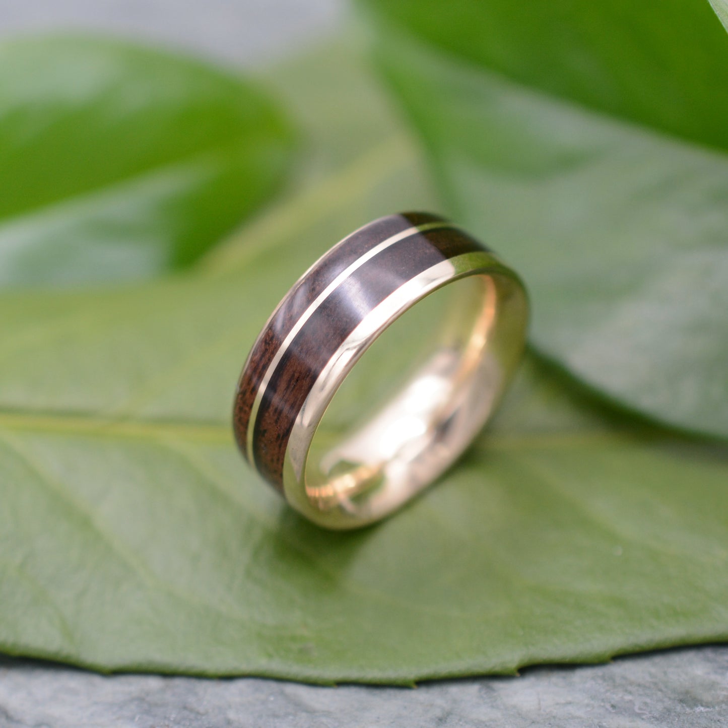 a wedding ring sitting on top of a green leaf