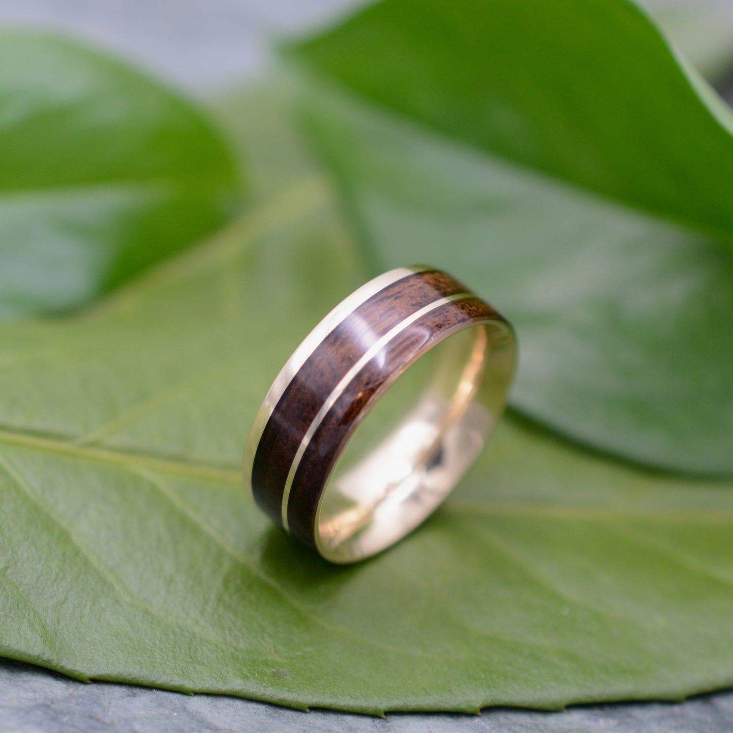 a wooden ring sitting on top of a green leaf