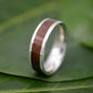 a wedding ring with a wooden inlay sits on a leaf