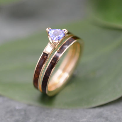 A gold ring with a blue gemstone, possibly a sapphire, is displayed on a green leaf.