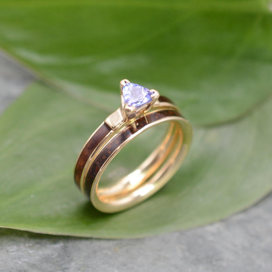 A gold ring with a blue gemstone, possibly a diamond, is displayed on a green leaf.