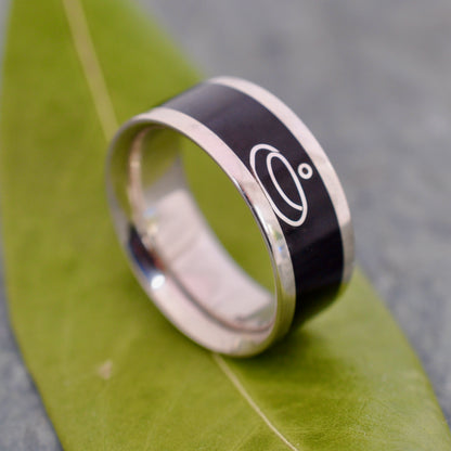 a black and silver ring on a green leaf