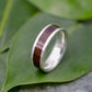 a wooden ring sitting on top of a green leaf