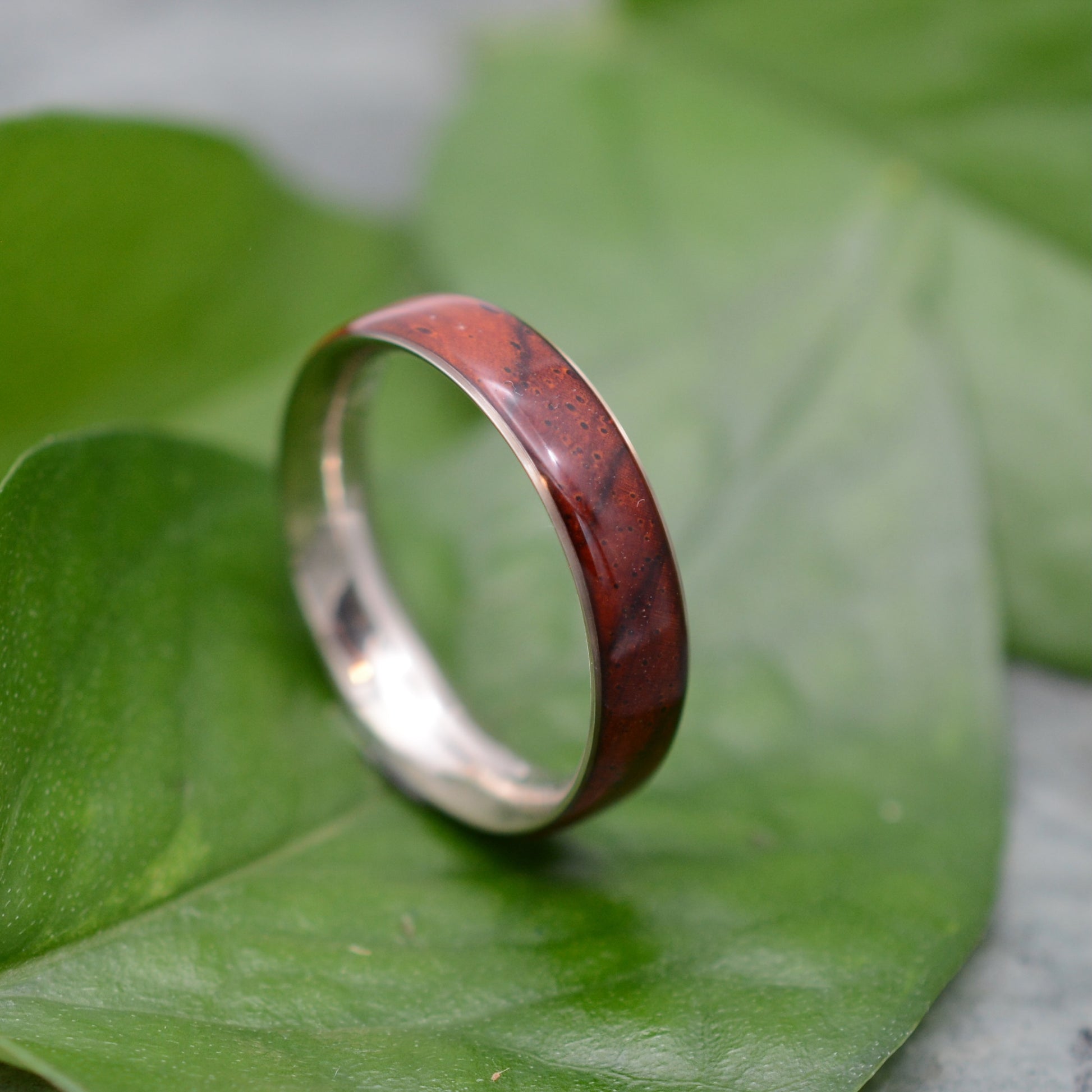 a silver ring with a red wood in it