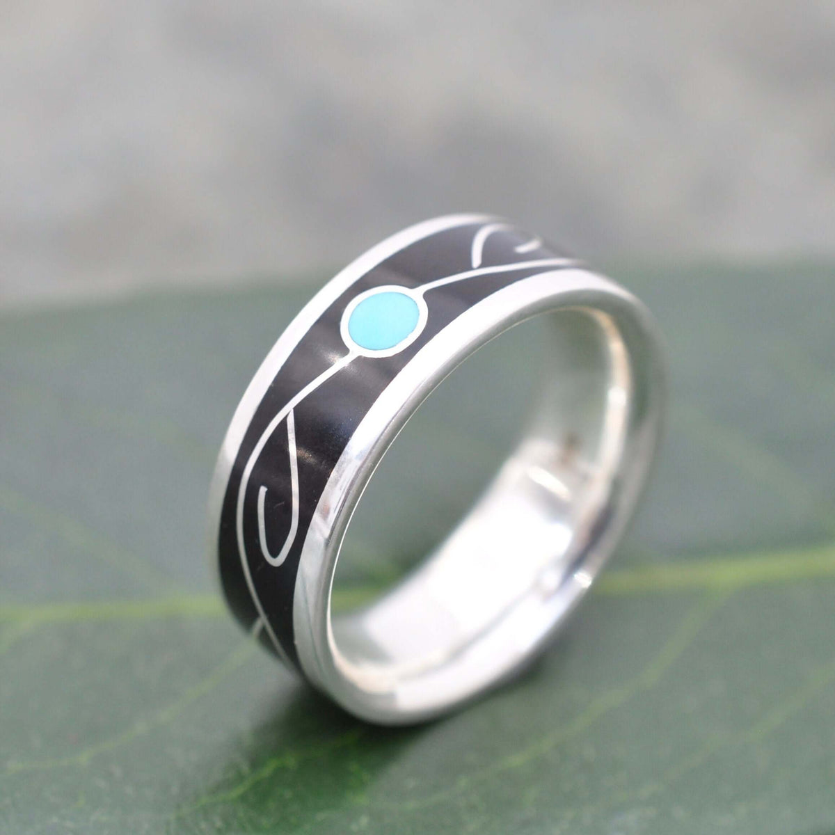 Close-up of turquoise vine inlay and black coyol seed in silver ring