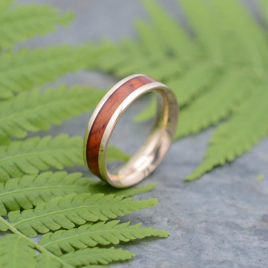 a gold ring with a wooden inlay on a fern leaf