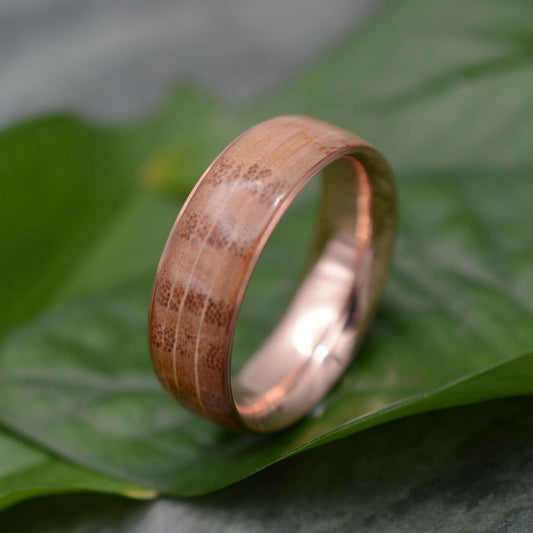 a wedding ring with a wooden inlay sits on a leaf