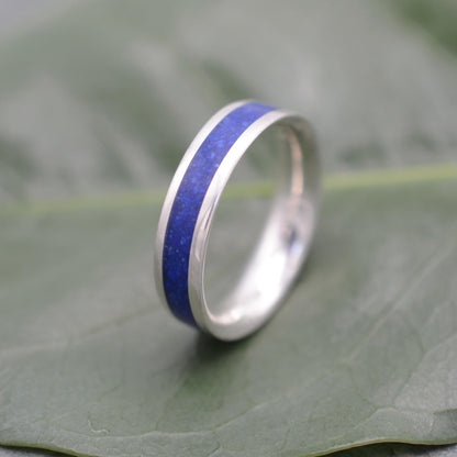 a wedding ring with a blue stripe on top of a leaf