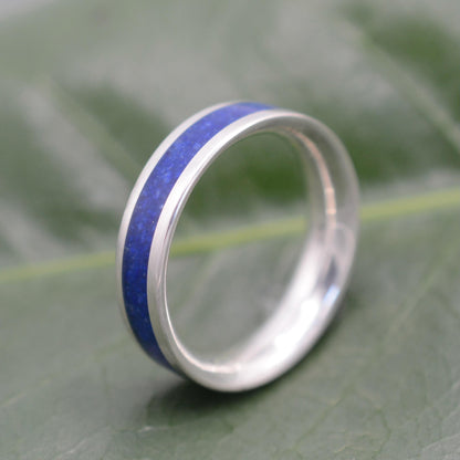 a wedding ring with a blue stripe on a green leaf
