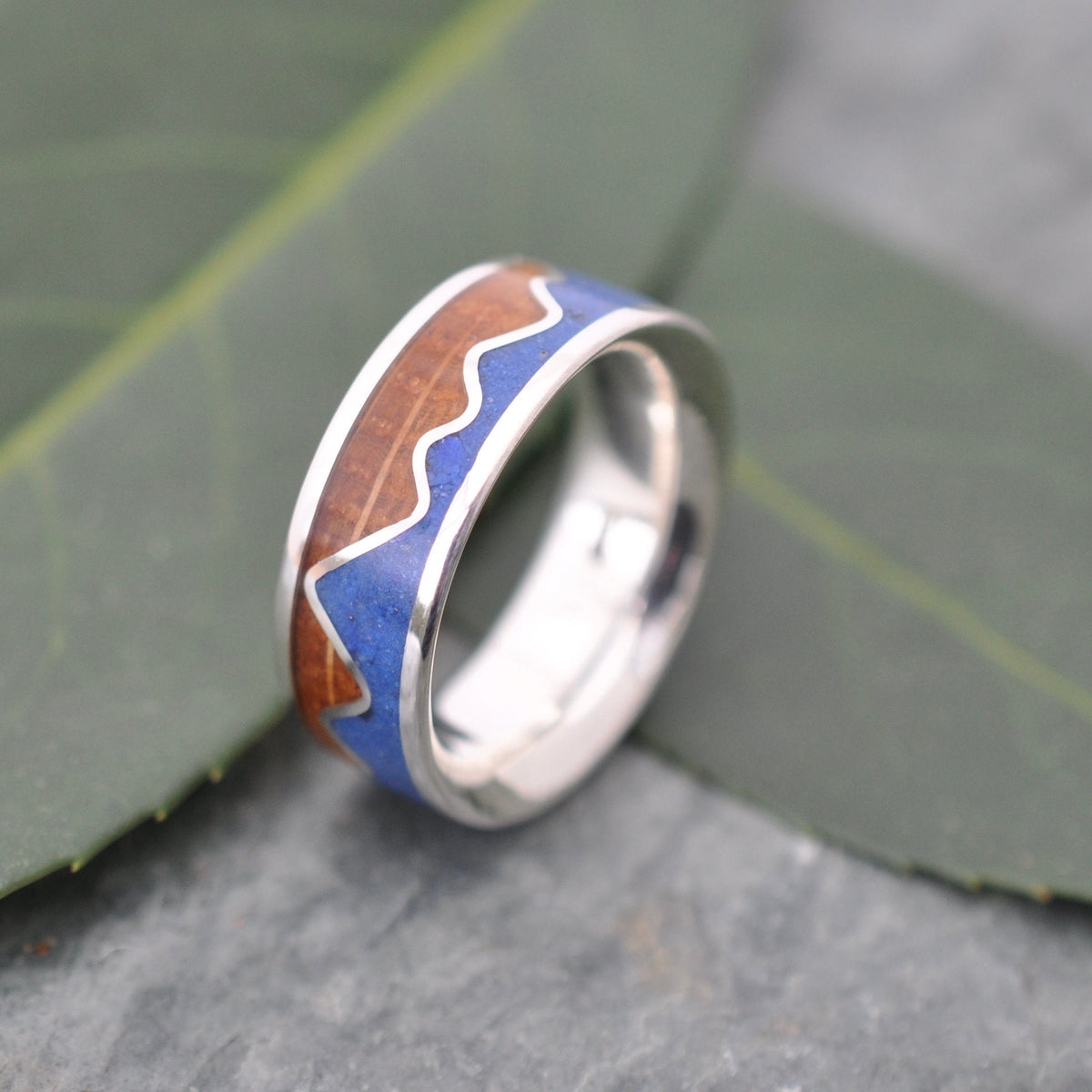 Lapis Lazuli Mountain Ring, Bourbon Barrel Wood and Sterling Silver displayed on a leafy surface, handcrafted and custom made.