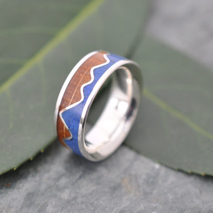 Lapis Lazuli Mountain Ring, Bourbon Barrel Wood and Sterling Silver displayed on a leafy surface, handcrafted and custom made.