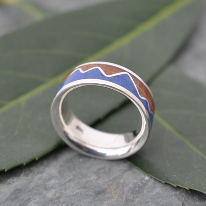 Lapis Lazuli Mountain Ring, Bourbon Barrel Wood and Sterling Silver showcased on leaves.