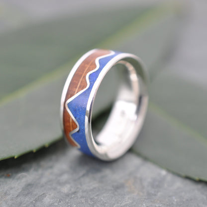 Lapis Lazuli Mountain Ring, Bourbon Barrel Wood and Sterling Silver on a leaf background, showcasing the unique inlay design.