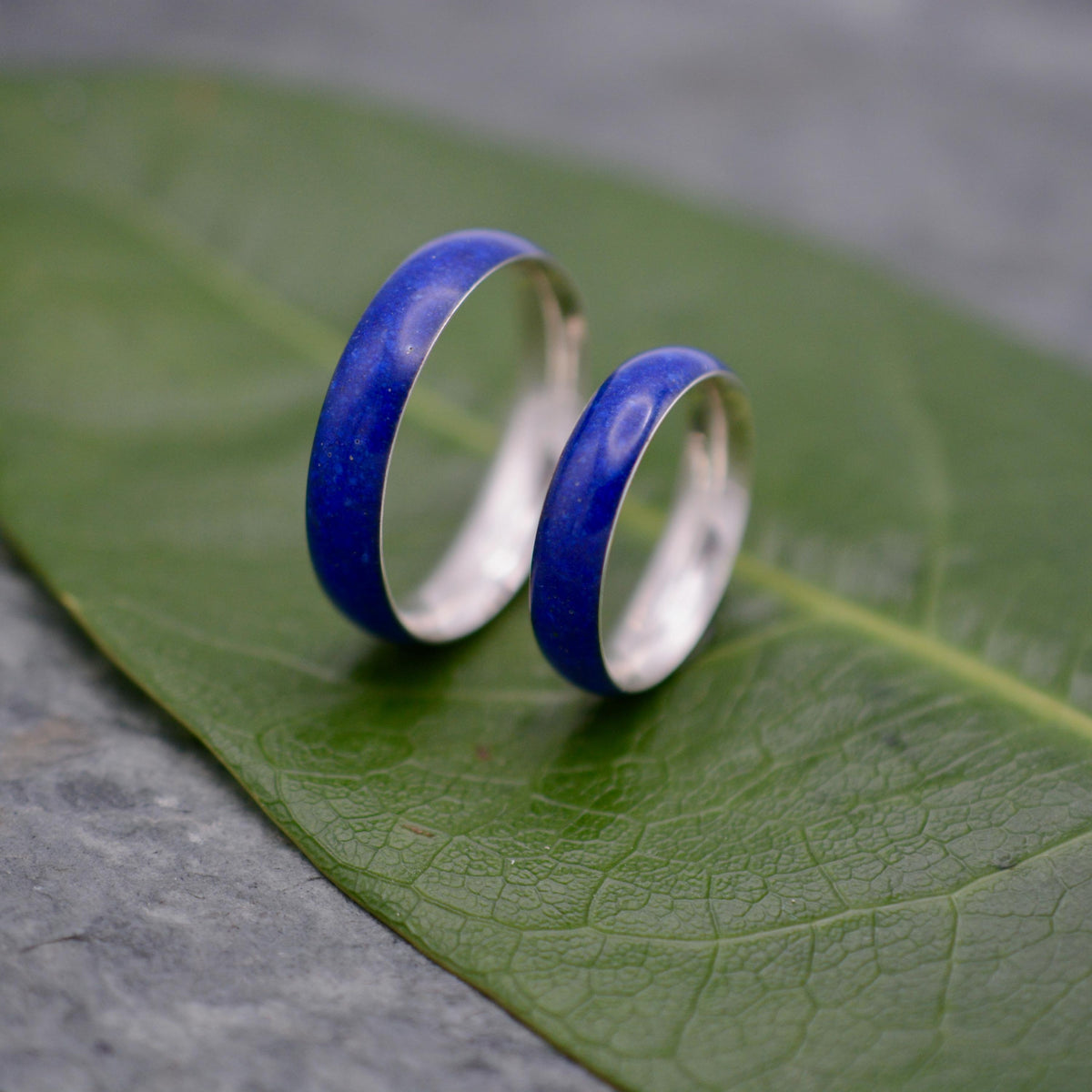 Two lapis lazuli silver wedding rings on green leaf, Siempre design