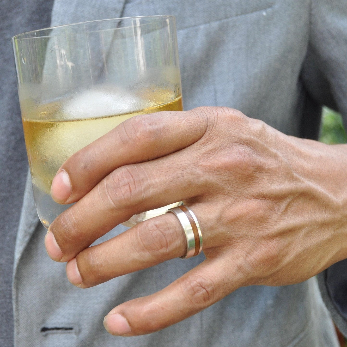 Bourbon barrel wedding band on finger showing wood grain detail