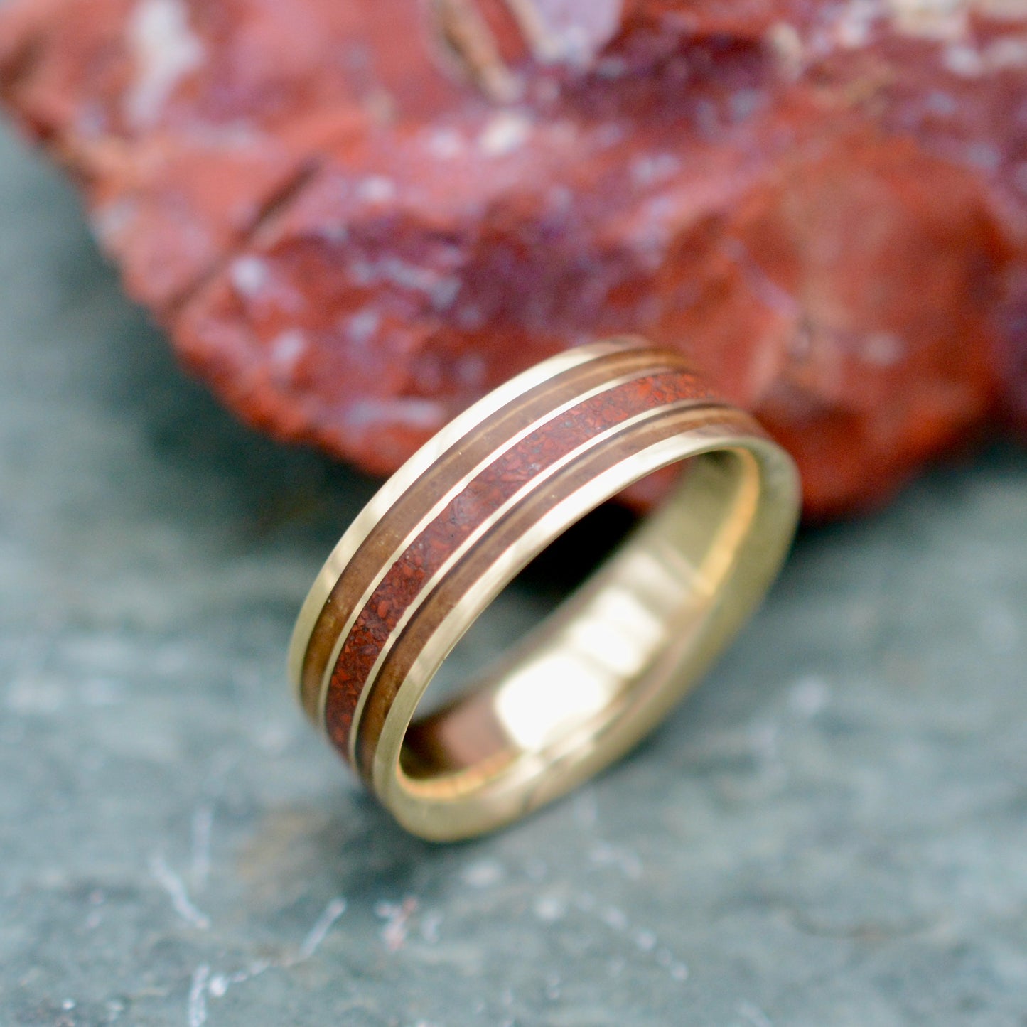 a gold wedding band with a wood inlay