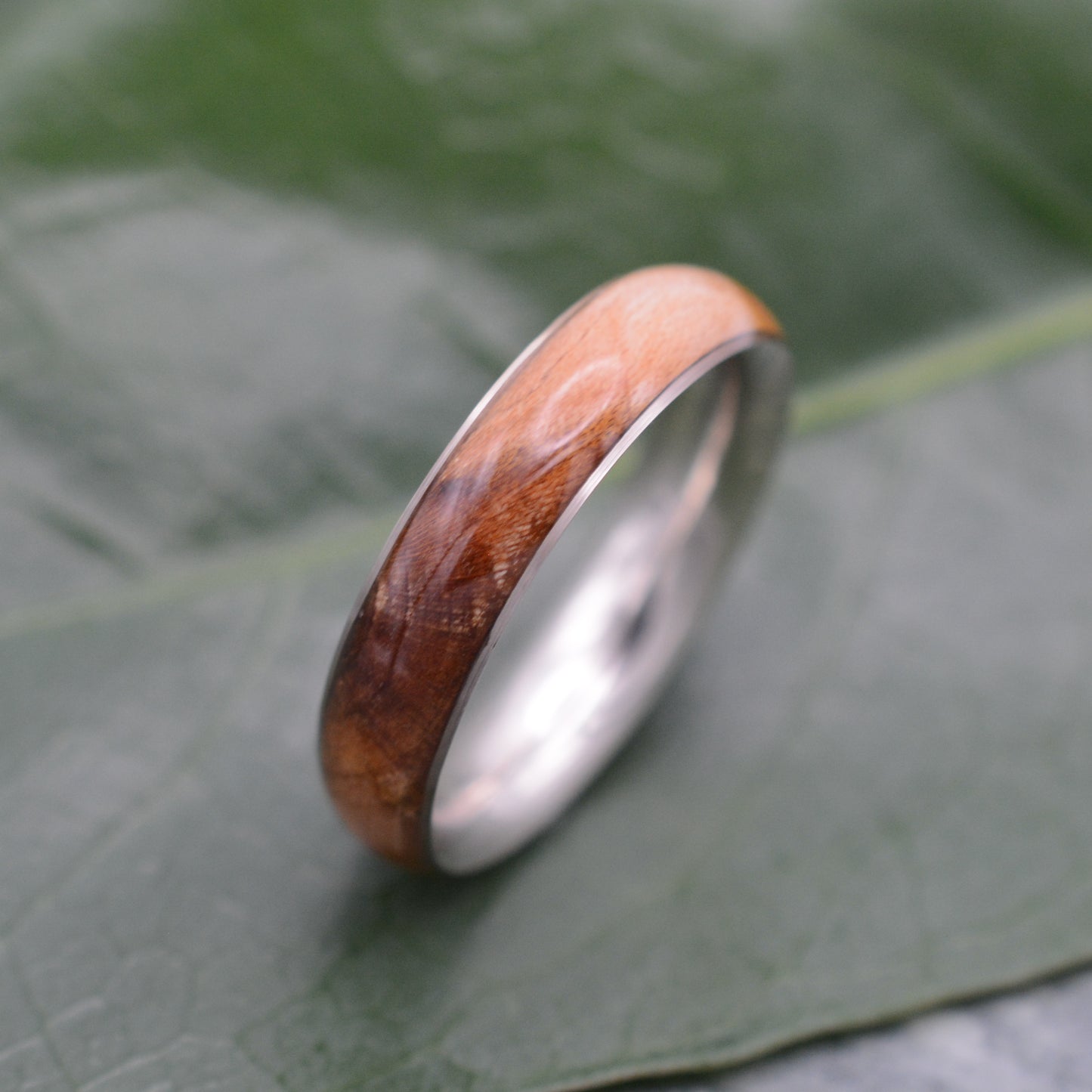 a wooden ring sitting on top of a green leaf