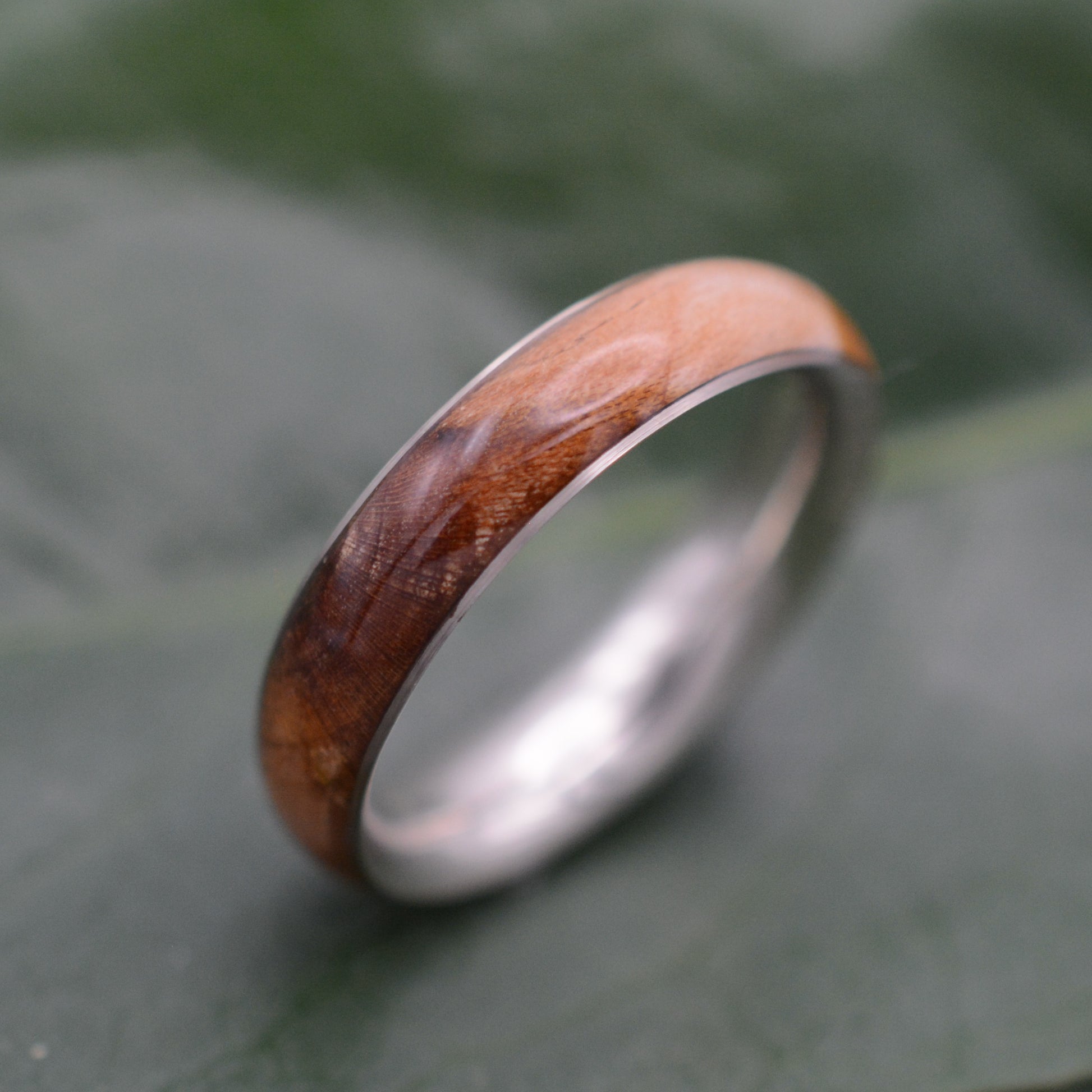 a wedding band with a wooden ring on top of a leaf