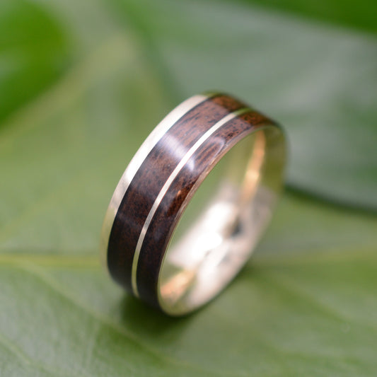a wedding ring with a wooden inlay on a green leaf