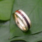 a gold ring with a red stripe on top of a leaf