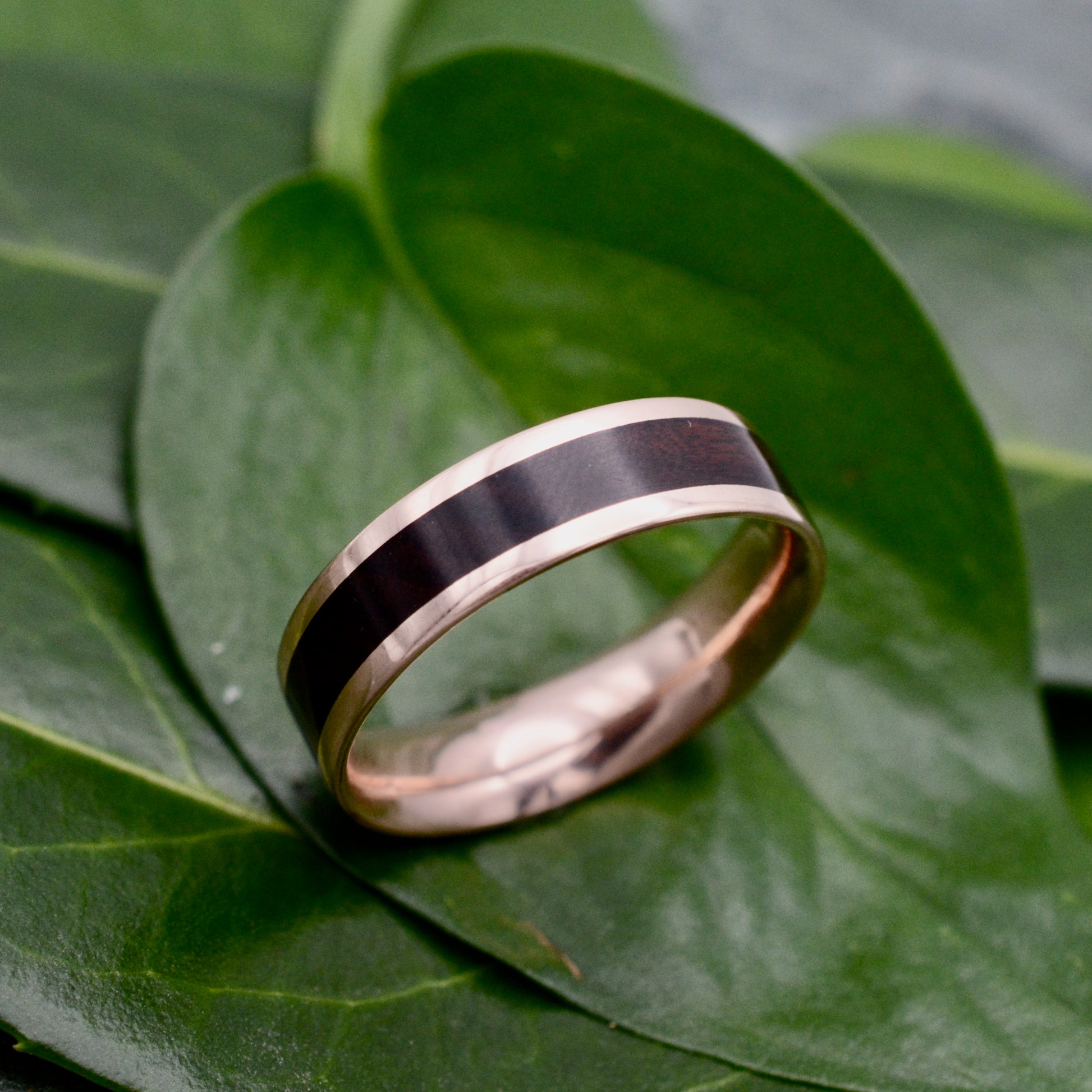 a wedding ring sitting on top of a green leaf