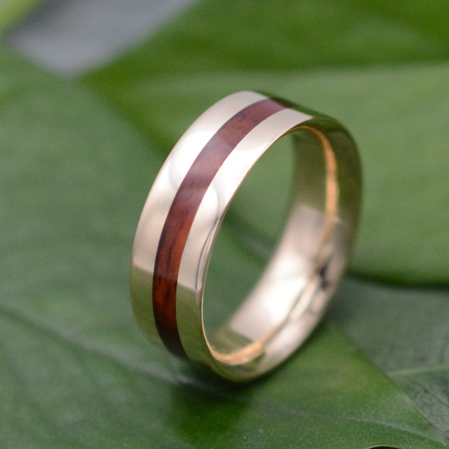 a gold ring with a wooden inlay on a green leaf