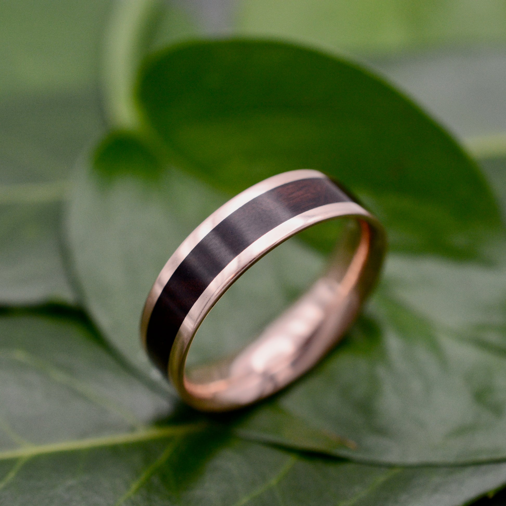 a wedding ring sitting on top of a green leaf