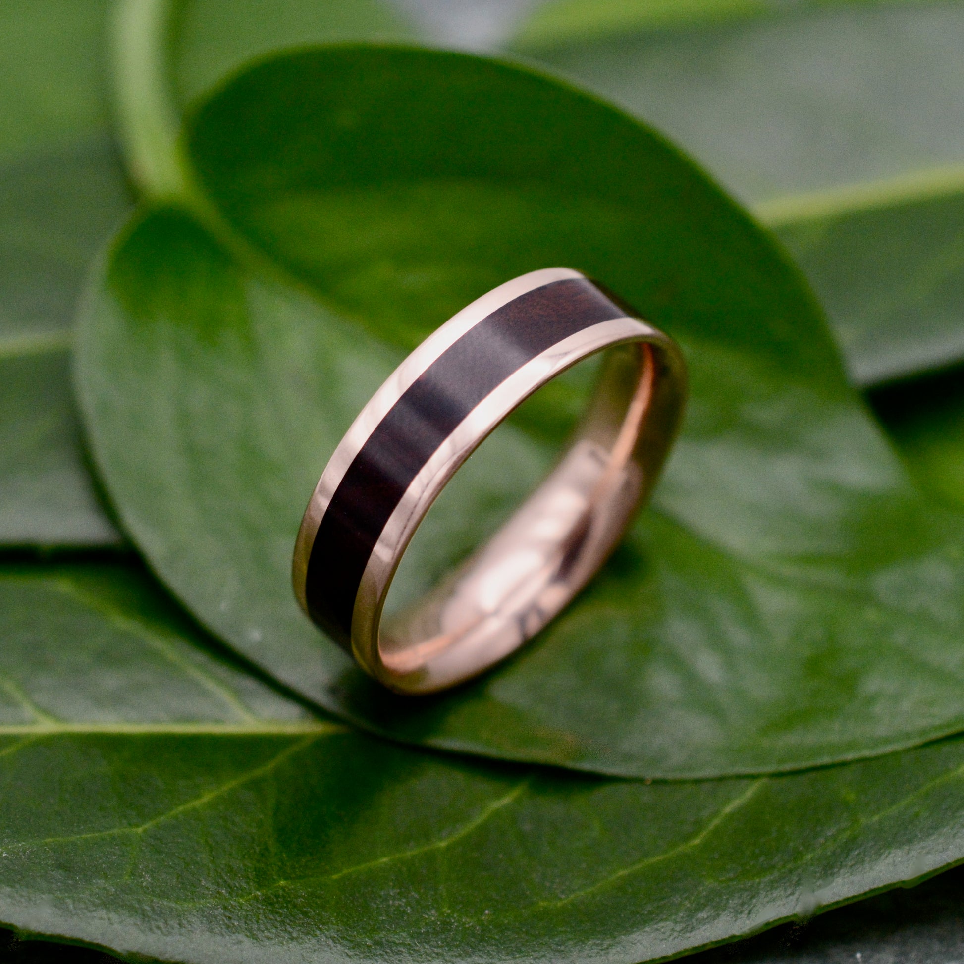 a gold ring with a black stripe on top of a leaf