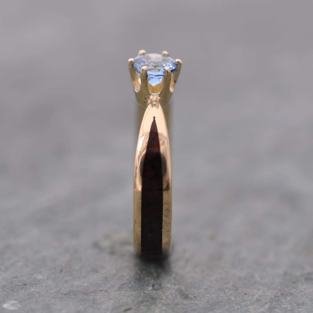 Close-up of aquamarine solitaire setting on custom wooden engagement ring in 14k yellow gold, ethically sourced March birthstone gemstone