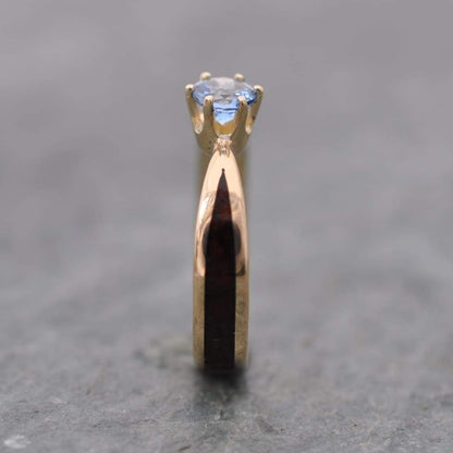 Close-up of aquamarine solitaire setting on custom wooden engagement ring in 14k yellow gold, ethically sourced March birthstone gemstone