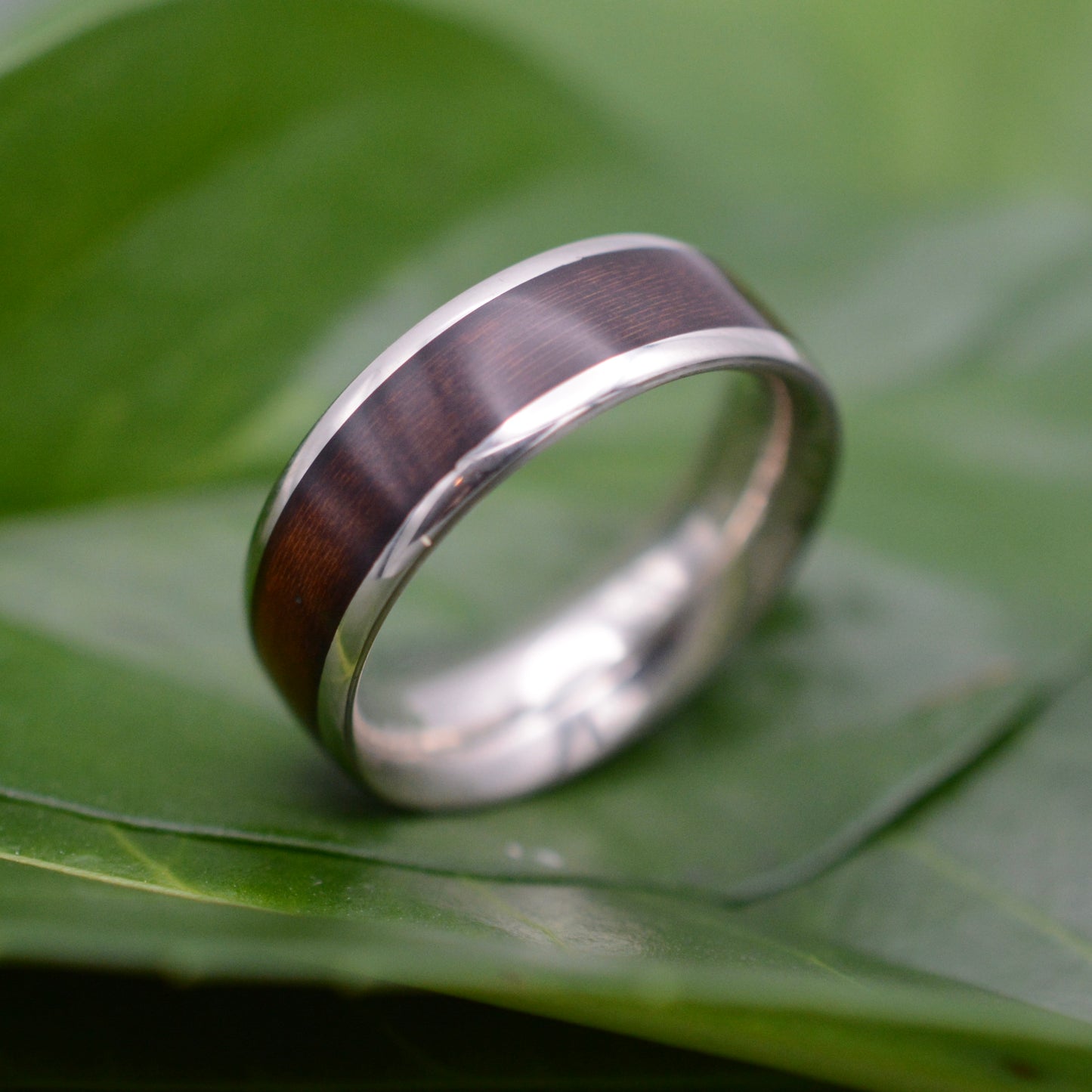 a wedding ring sitting on top of a green leaf