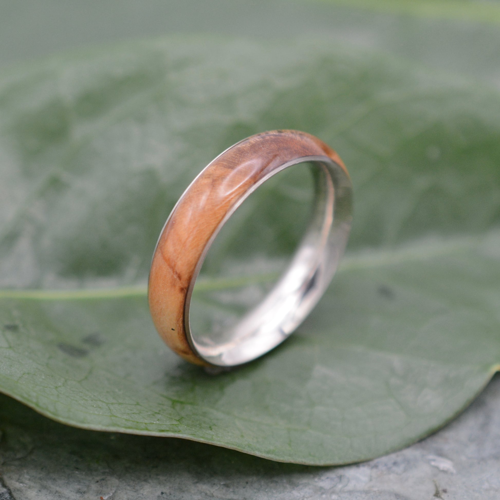 a wooden ring sitting on top of a leaf