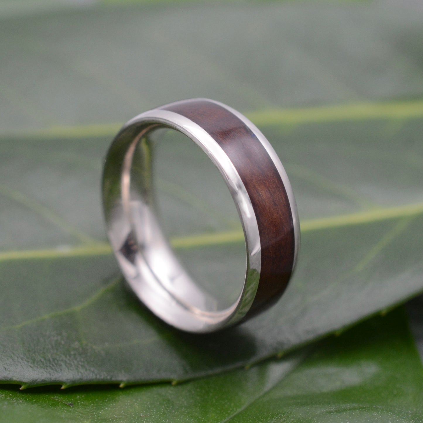 a silver ring with a wooden inlay on a leaf