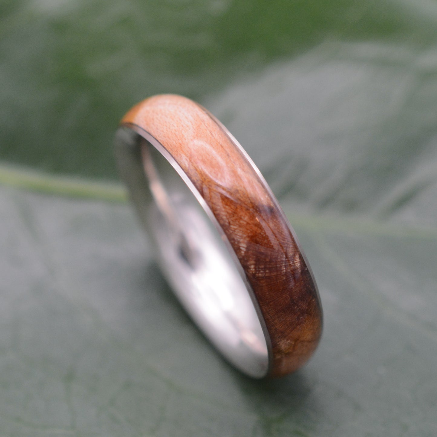 a wooden ring sitting on top of a leaf