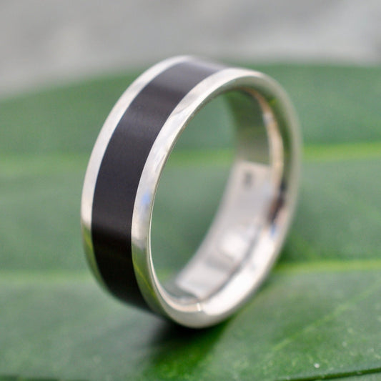 Lados Comfort Fit Lados Coyol Wood Sterling Silver Edges Wedding Ring on a leaf background, showcasing a unique wood wedding ring.