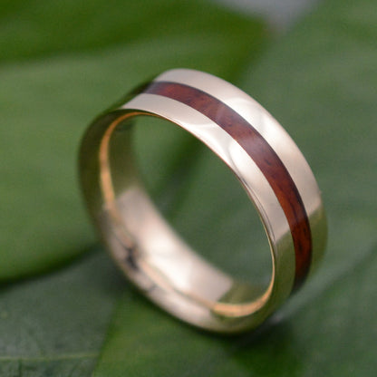 a gold ring with a wooden inlay on a green leaf