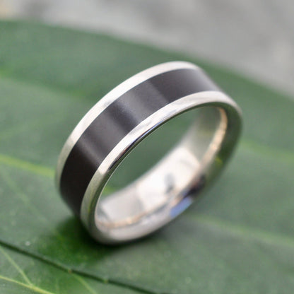 Lados Comfort Fit Lados Coyol Wood Sterling Silver Edges Wedding Ring on a leaf, showcasing wood wedding ring craftsmanship.