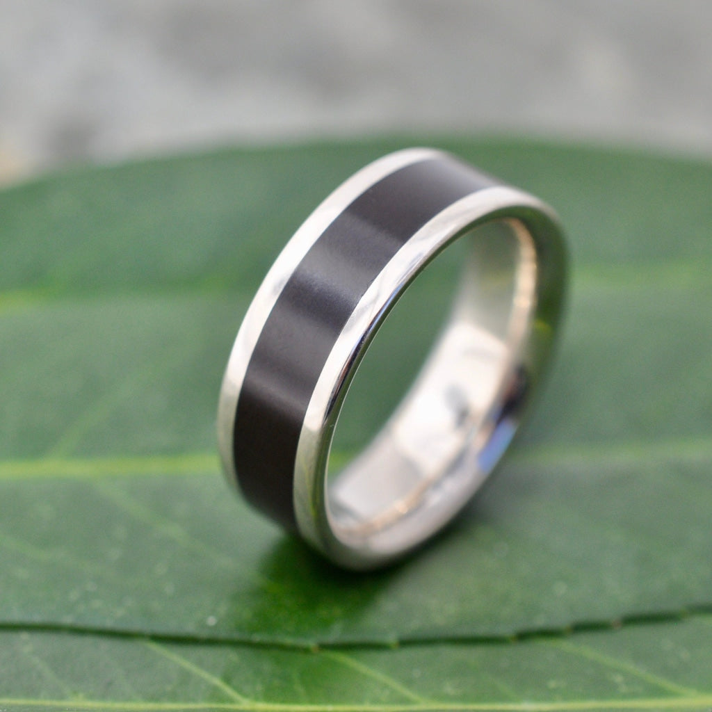 Lados Comfort Fit Lados Coyol Wood Sterling Silver Edges Wedding Ring on green leaf background, handcrafted in Louisville KY.