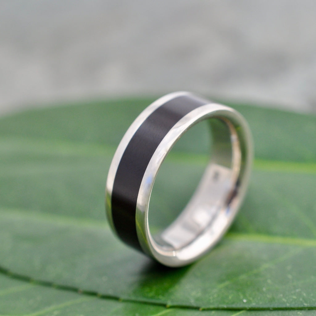 Lados Comfort Fit Lados Coyol Wood Sterling Silver Edges Wedding Ring on a leaf, a stylish wood wedding band.