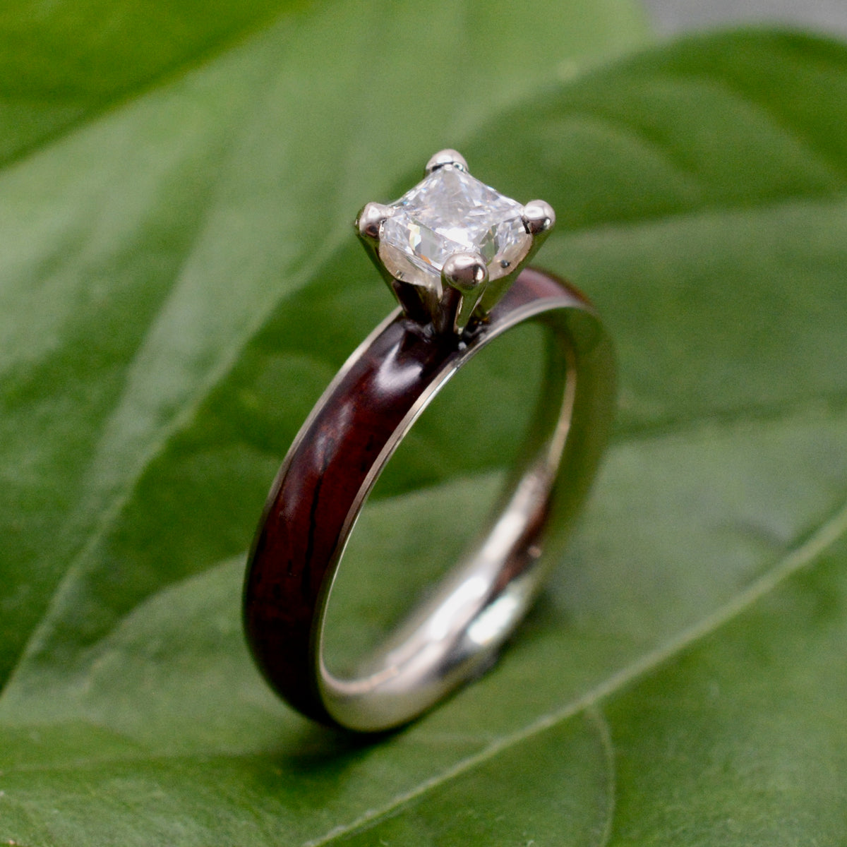 Princess cut diamond wood engagement ring with cocobolo wood band on natural background